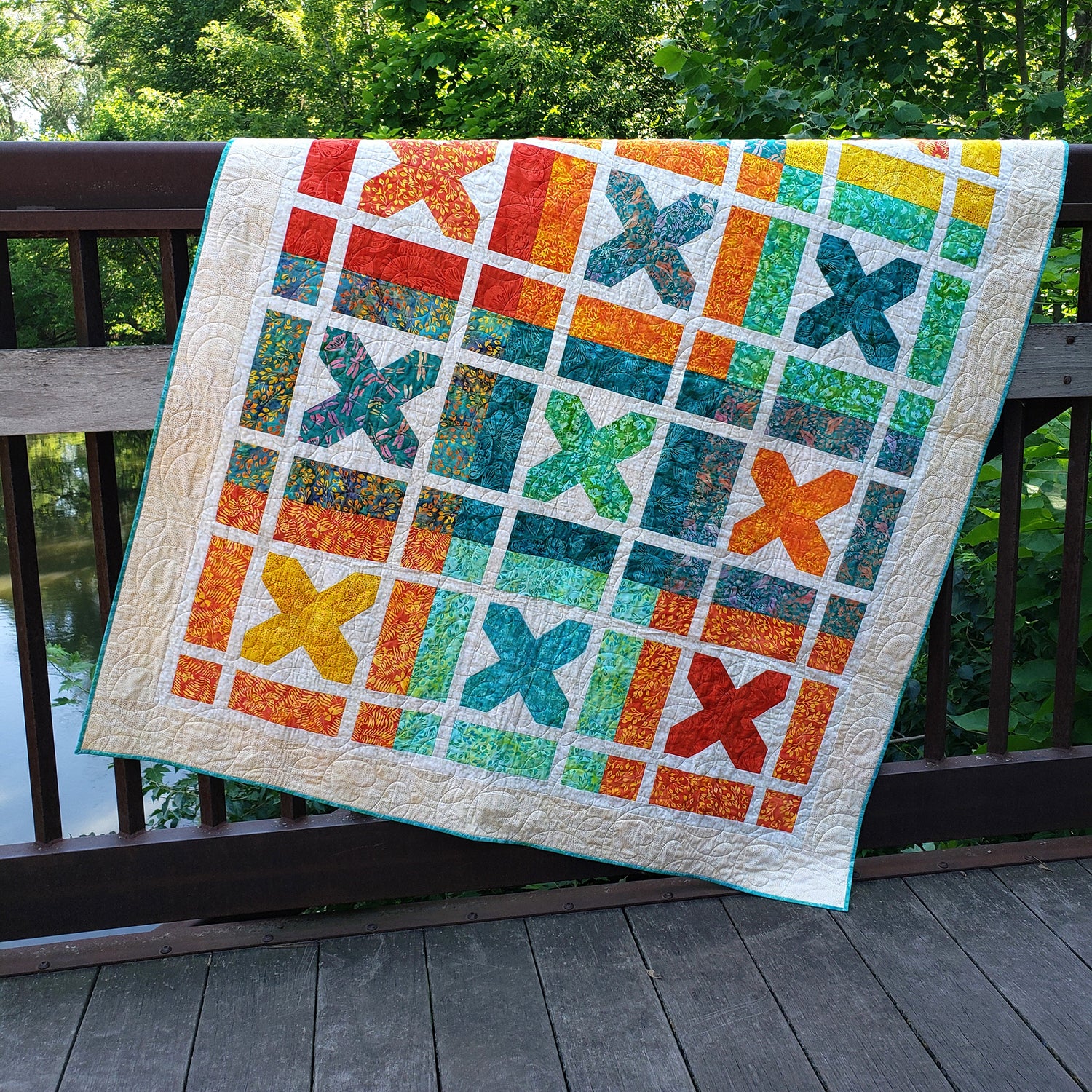 Bright and fun Kisses quilt features blocks of X's which represent Kisses. Each block is a bright color with white background inside with a bight colored X.