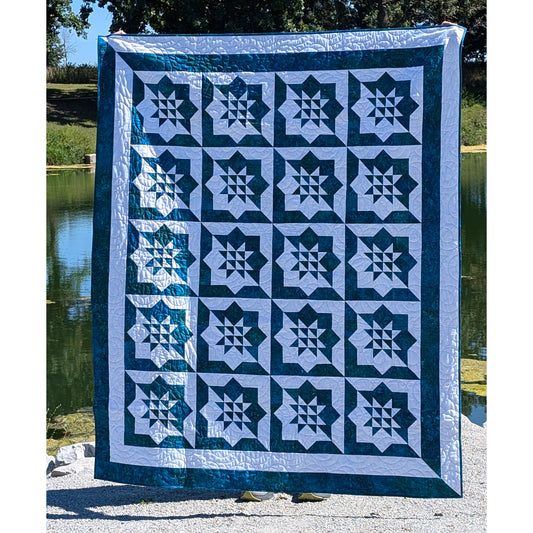 A person lifts a quilt adorned with a blue and white stars design.