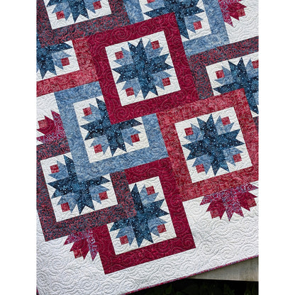 Close up of the beautiful and fun quilt features overlapping star blocks with bold and wide borders to help with the overlapping look. A few additional stars peek out here and there outside those blocks to give a peek-a-boo effect.