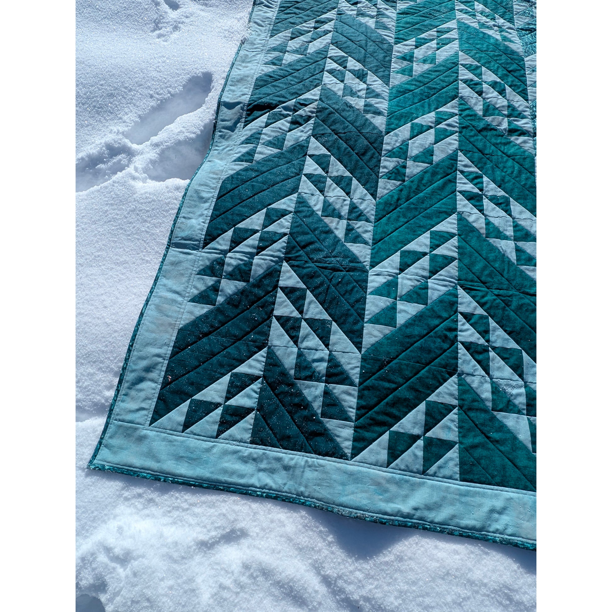 Close up of quilt featuring rows of solid slanted rectangles and ones filled with triangles.  The left rows are darker than the ones on the right.