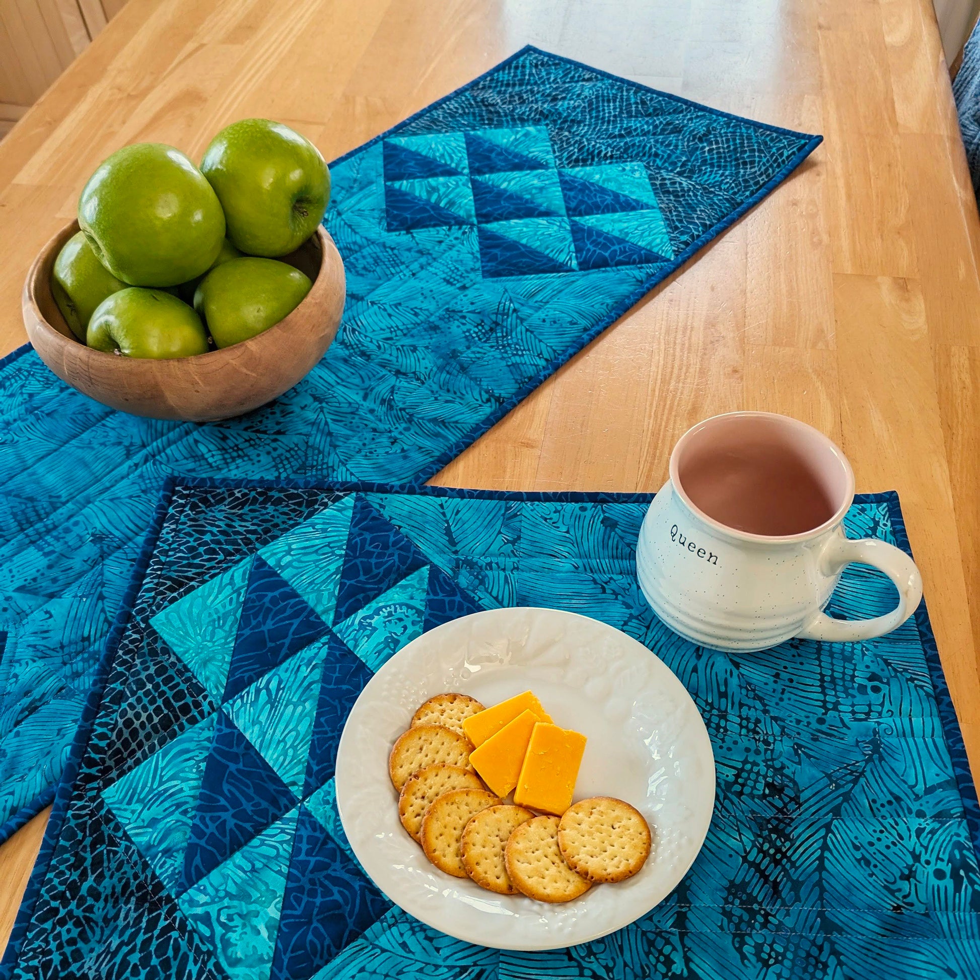 Simple clusters of HST units set on point are the focal point of this elegant, quilted table pattern.  Shown here in blues.  One side of the place mat has the half-square-triangles and the other is a solid fabric. Table runner has the design on both sides with lots of space in the middle for run quilting.