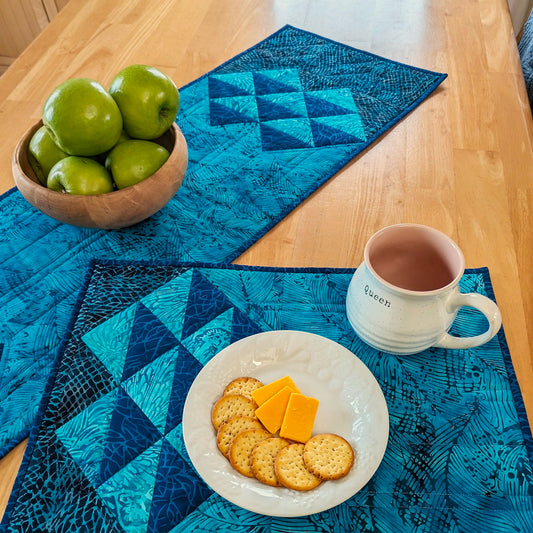 Simple clusters of HST units set on point are the focal point of this elegant, quilted table pattern.  Shown here in blues.  One side of the place mat has the half-square-triangles and the other is a solid fabric. Table runner has the design on both sides with lots of space in the middle for run quilting.
