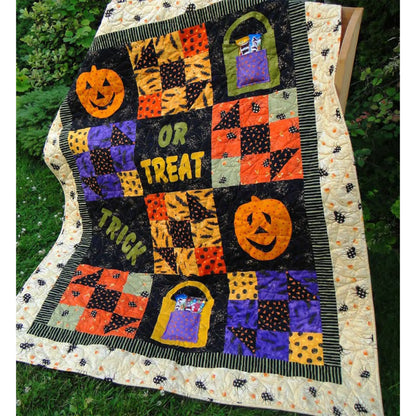 Adorable quilt showcased in a garden with squares of jack-o-lanterns, bags of candy (with real candy inside), pieced candy shape and words "trick or treat".