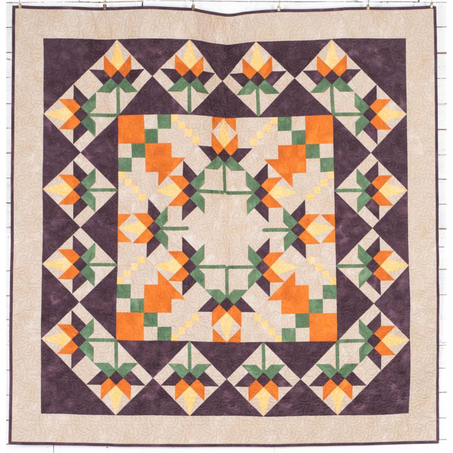 Beautiful quilt features orange flowers in the middle, with a fun pattern for the leaves and in squares around the outside.  Fun for any season.