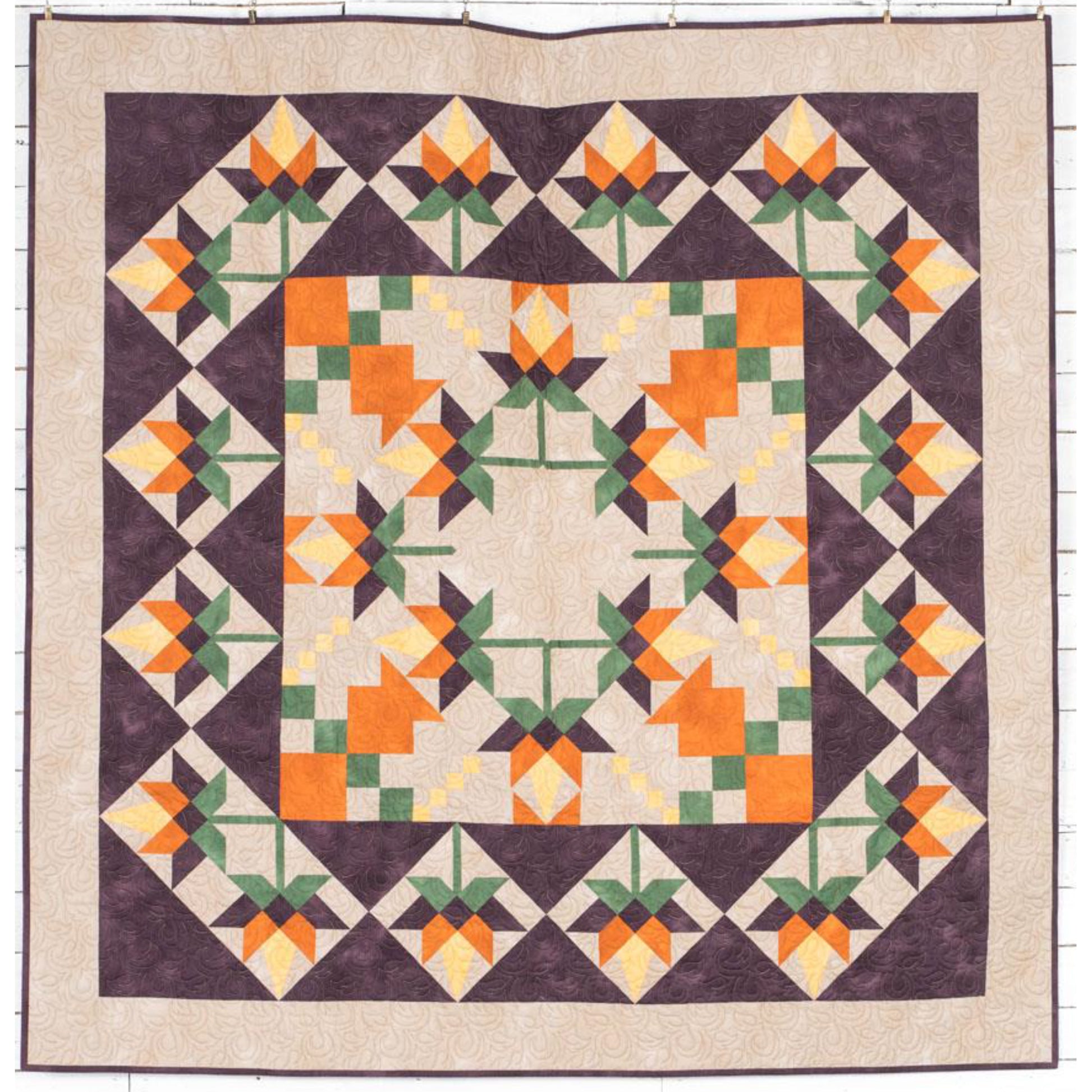 Beautiful quilt features orange flowers in the middle, with a fun pattern for the leaves and in squares around the outside.  Fun for any season.