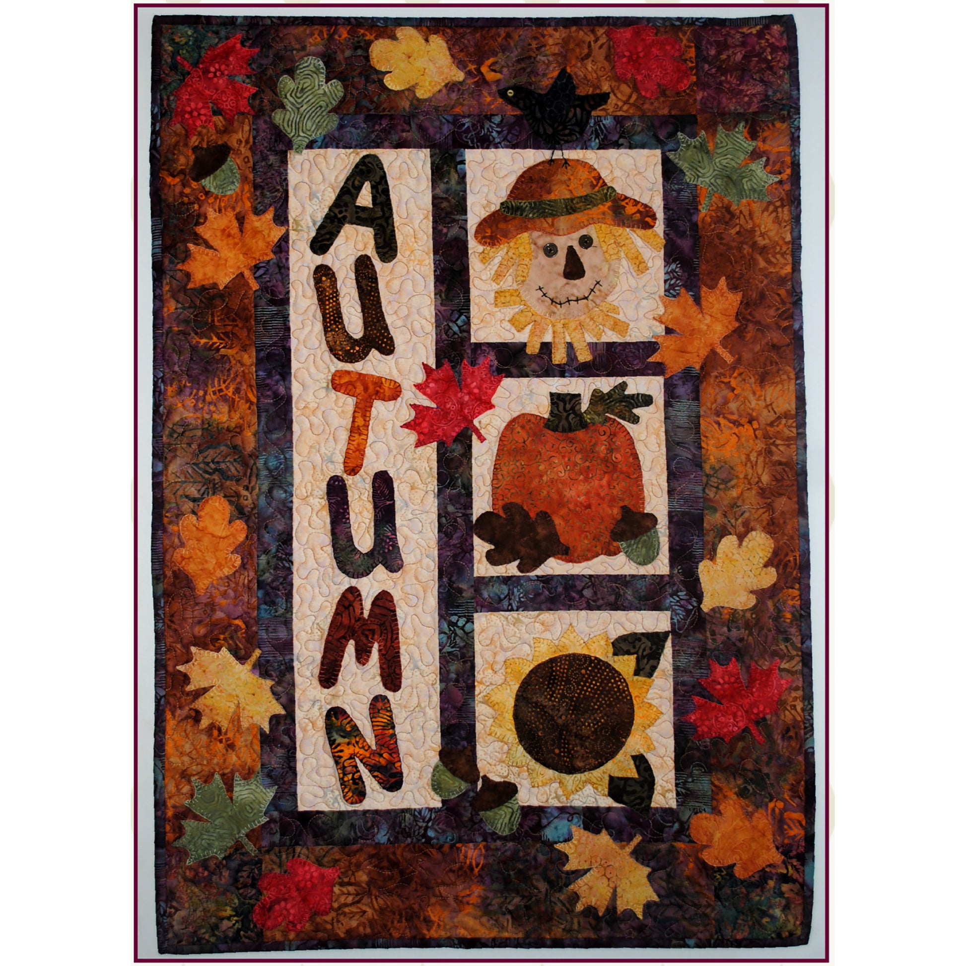 Fall and Autumn themed quilt wall hanging with falling colored leaves, the word "Autumn", scare crow, pumpkin and sunflower.