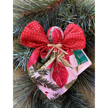 Angel ornament hanging on a tree shows gift card and candy from pocket.