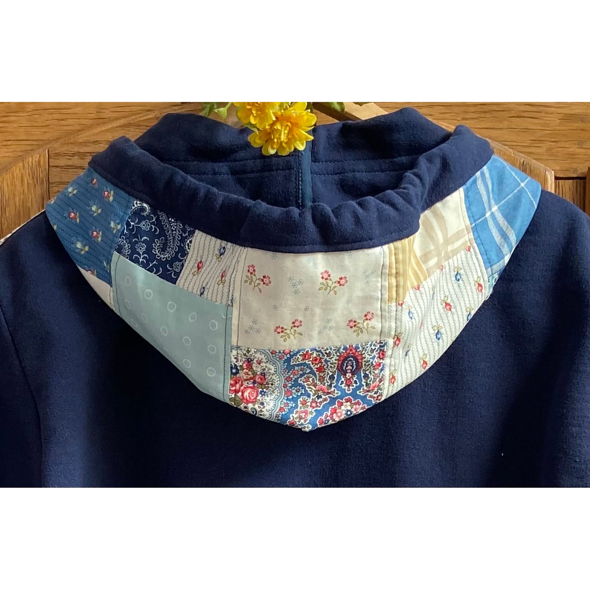 Showing the hoodie at the back of the sweatshirt with cute patchwork design to match the front (other photo). This one is a blue sweatshirt with white and blue fabric.