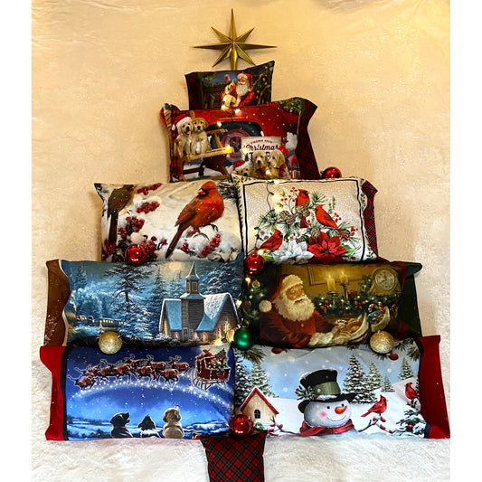 Pile of pillows on a bed stacked like a tree with a star at the time. The pillowcases are all Christmas related designs and come in multiple sizes. Each includes a large print fabric.