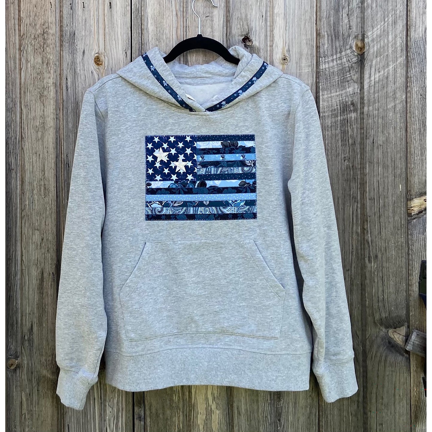 Grey hoodie sweatshirt with blue American flag with blue fabric in the middle.