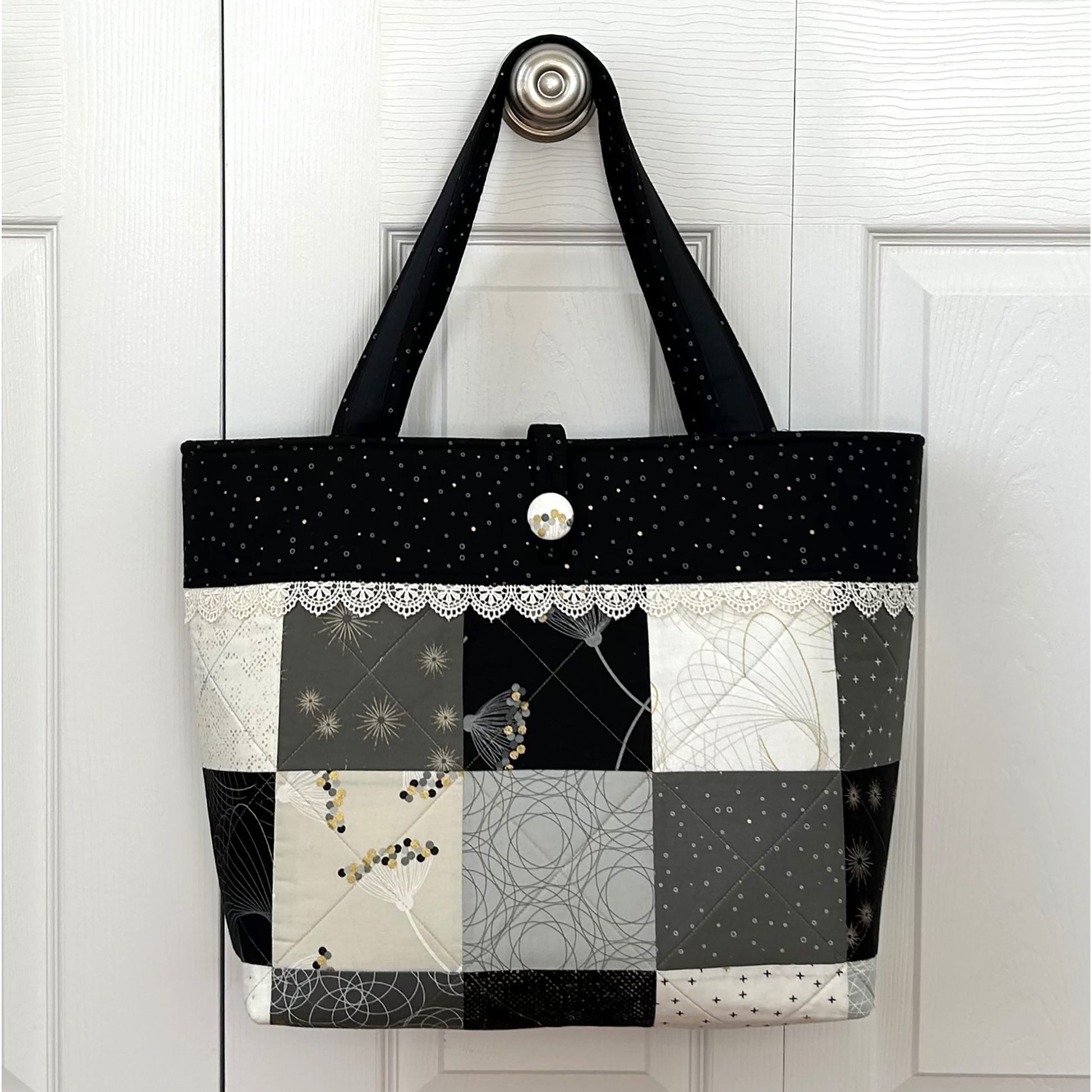 Adorable tote bag using a Charm Pack. It has a back zippered pocket to hold all your treasures. Fabrics in neutral colors with a cute lace border under the top band.