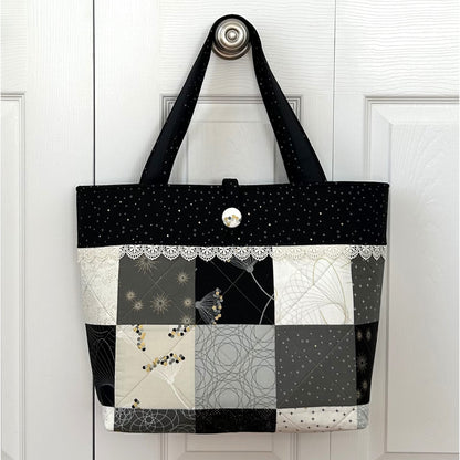 Adorable tote bag using a Charm Pack. It has a back zippered pocket to hold all your treasures. Fabrics in neutral colors with a cute lace border under the top band.