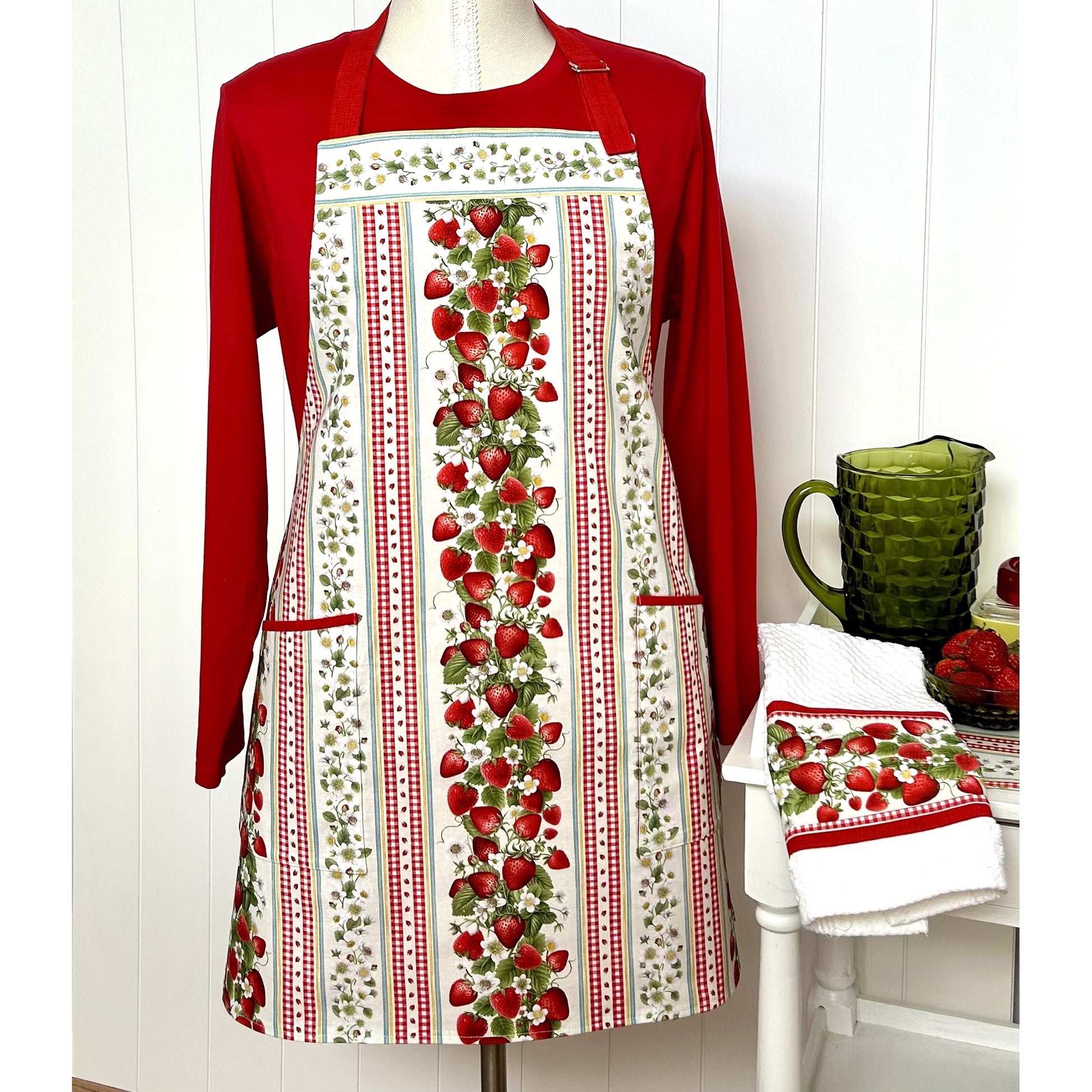A one-of a kind apron using border stripe fabric. The apron is fully lined with pocket options. Make coordinating kitchen towels from leftover scraps.  Image shows the one in strawberries print.