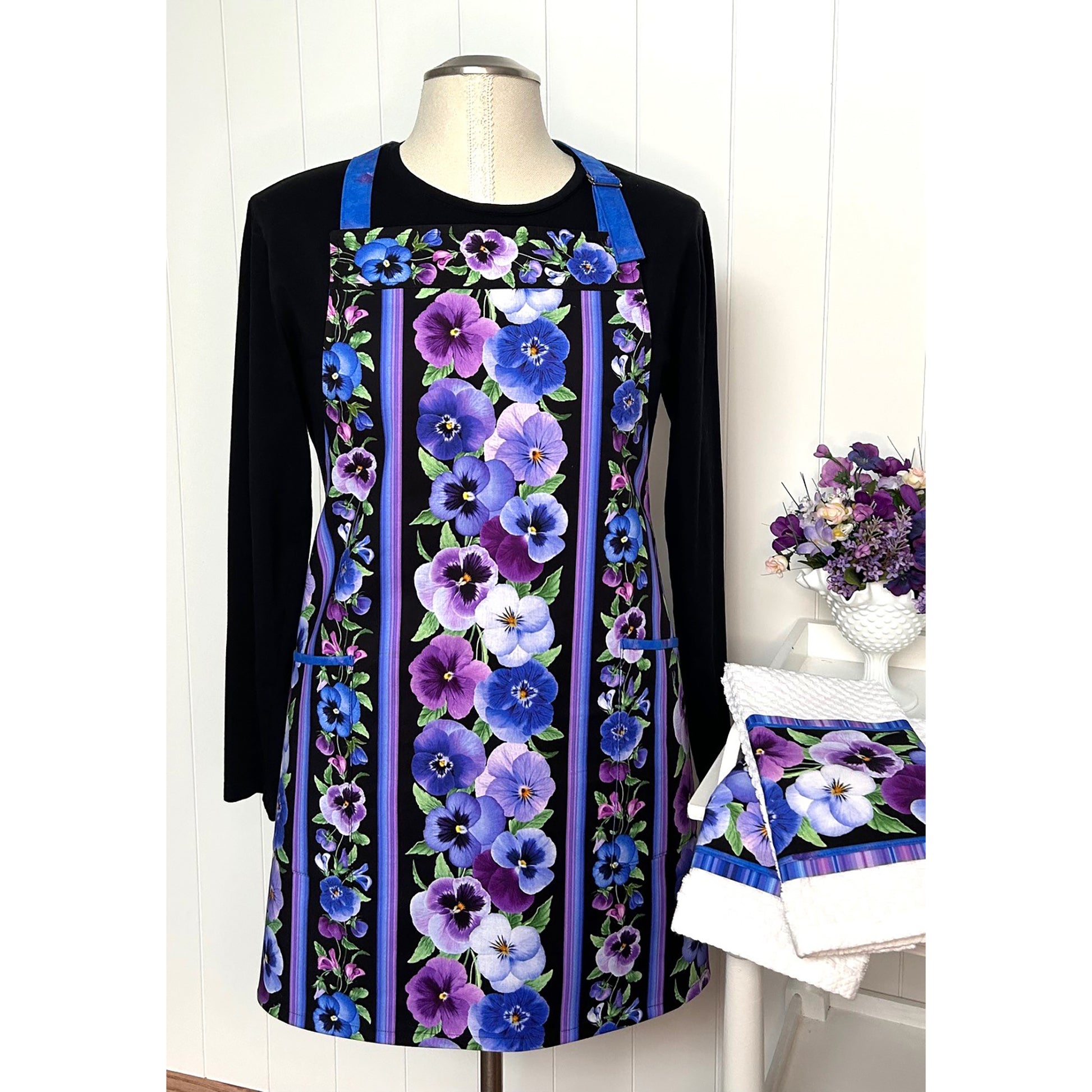 A one-of a kind apron using border stripe fabric. The apron is fully lined with pocket options. Make coordinating kitchen towels from leftover scraps.  Image shows the one in pansies print.