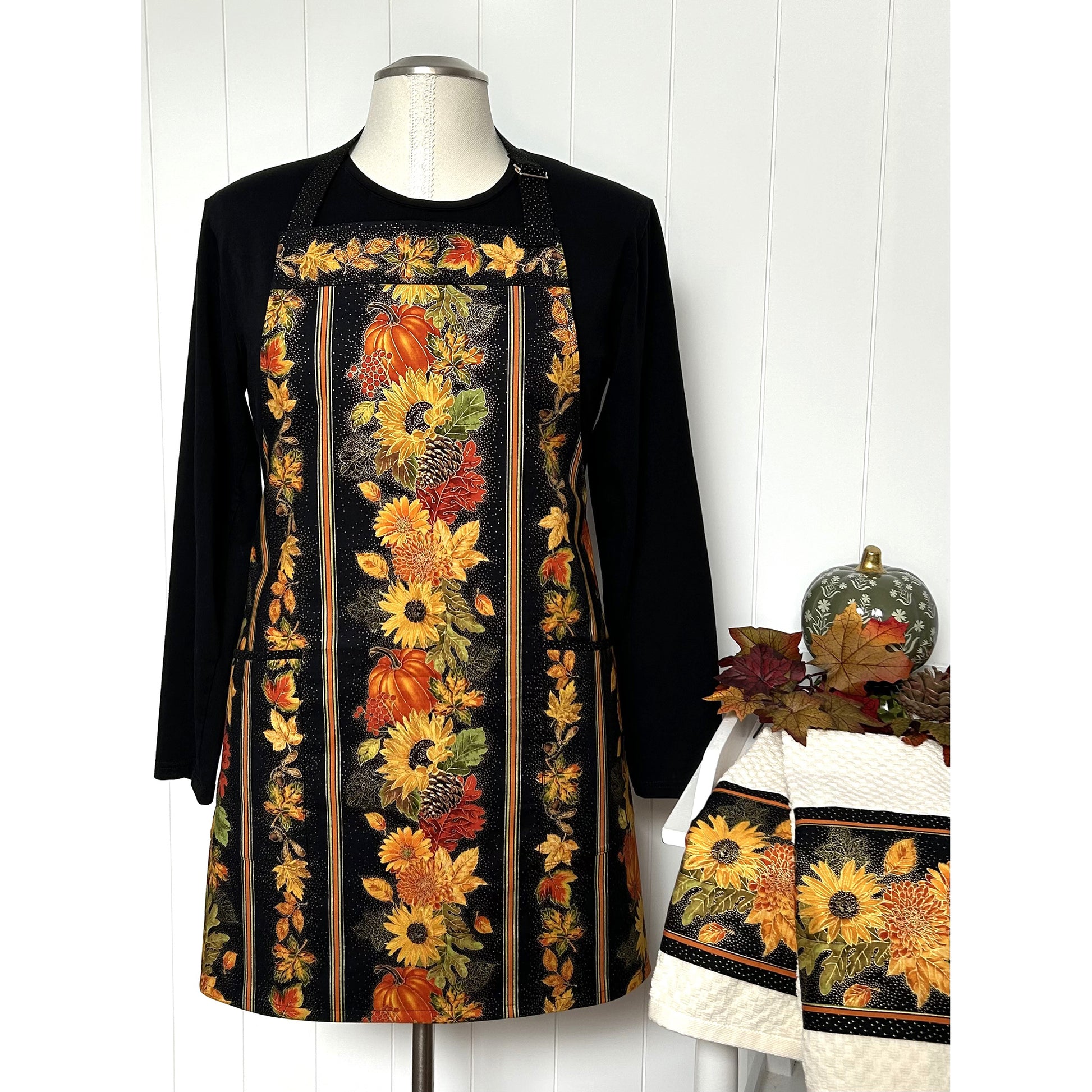 A one-of a kind apron using border stripe fabric. The apron is fully lined with pocket options. Make coordinating kitchen towels from leftover scraps.  Image shows the one in sun flowers and pumpkins print.