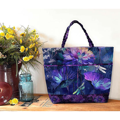 Tote bag with floral and dragonfly design on a wooden surface with flowers and a jar.