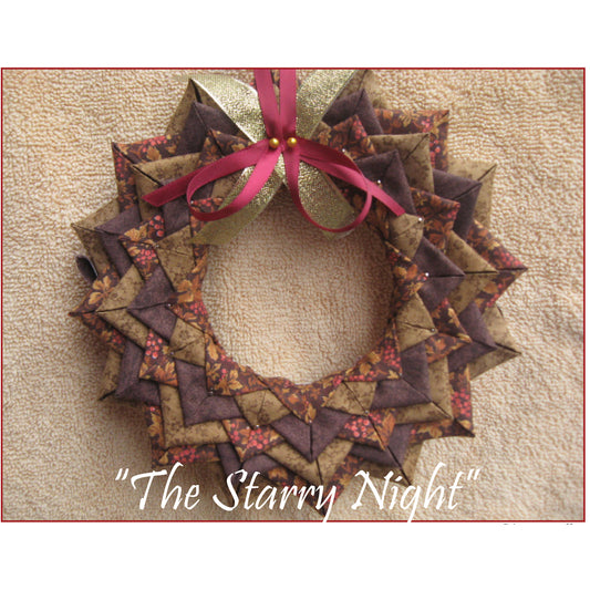 Beautiful wreath in brown fabric. There is a red ribbon pinned to the top and you can see some of the pins from the layers of fabric covering the wreath.