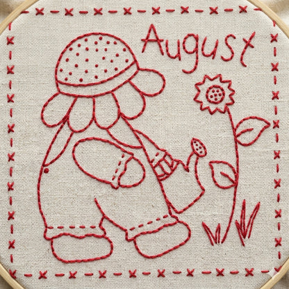 Redwork design featuring Sunbonnet Sue watering flowers while wearing a sunflower hat.