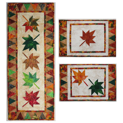 Three maple leaf items: long table runner with falling maple leaves down the middle and two place mats. One has one maple leaf and the other has two maple leaves.