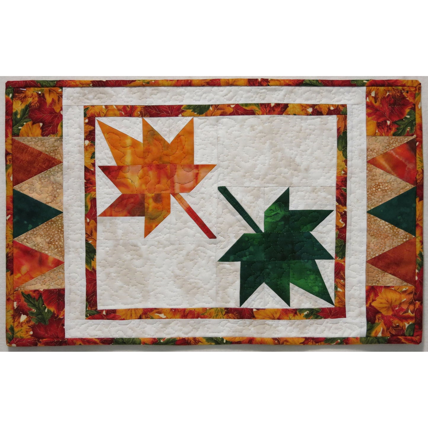 Place mat with two maple leaves in the middle - one is orange and one is green.