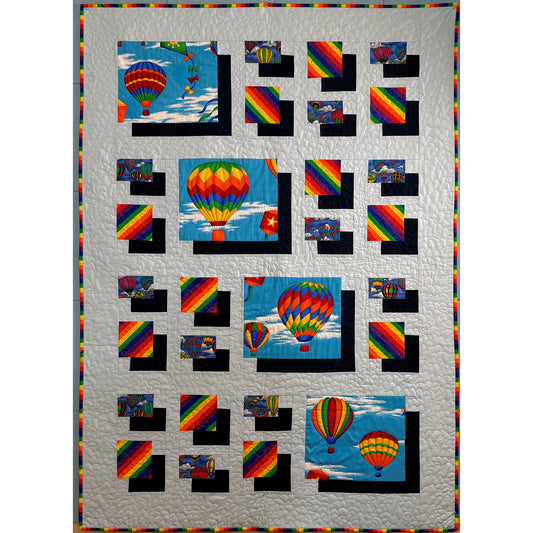 Bright hot air balloon quilt features small and large blocks of bright hot air balloons with shadowing to make them look like pebbles on the gray background fabric.