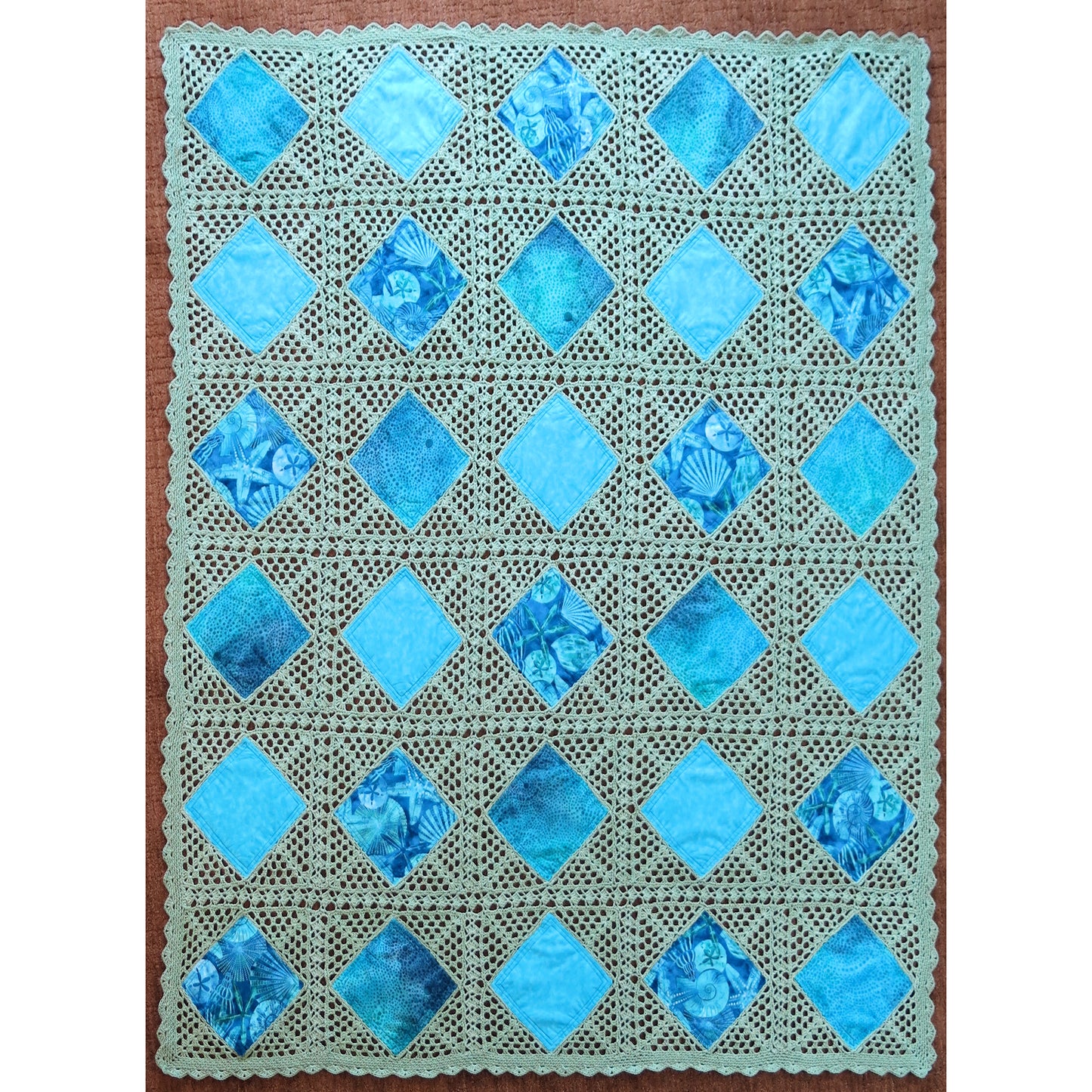 Beautiful quilt features diamonds of blue fabric crocheted together in a neutral cream thread.