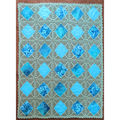 Beautiful quilt features diamonds of blue fabric crocheted together in a neutral cream thread.
