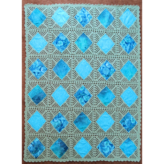 Beautiful quilt features diamonds of blue fabric crocheted together in a neutral cream thread.