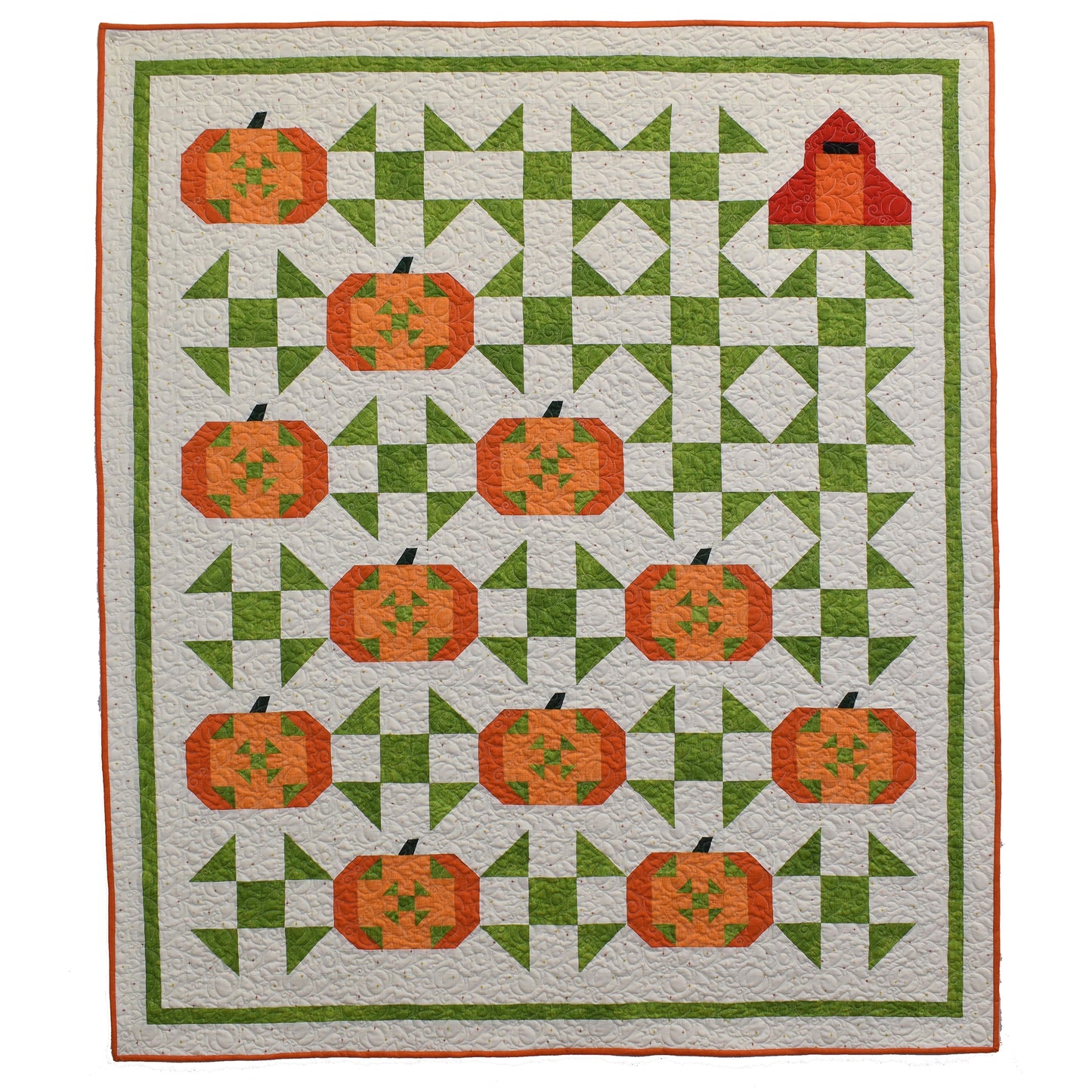 Beautiful fall quilt features vibrant pumpkins with a rustic barn in the upper right corner. There are blocks of diamonds and blocks between pumpkins in green.