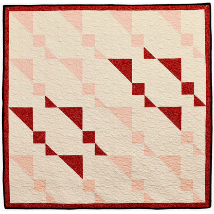 Twin Sisters quilt sparkles with holiday shimmer. The wall hanging features twin, abstract stars with others in light colors.