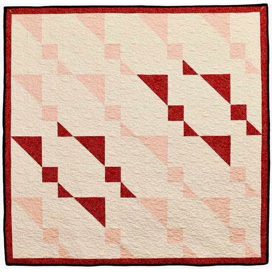 Twin Sisters quilt sparkles with holiday shimmer. The wall hanging features twin, abstract stars with others in light colors.