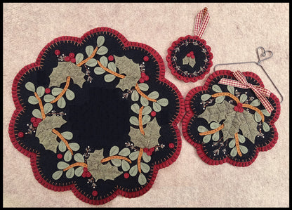 Three wool felt mats. Largest has vines and mistletoe with a clear center perfect for a candle. The medium sized one has a sprig of mistletoe and vines. Smallest is an ornament with two leaves of mistletoe.