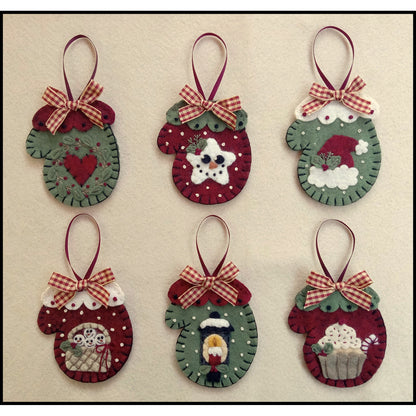 Six adorable wool felt ornaments in the shape of a mitten. Each has a different embroidered design on the red or green mitten.  Designs include a heart, star with face, Santa's hat, snowman in a basket, candle street light, and cupcake.