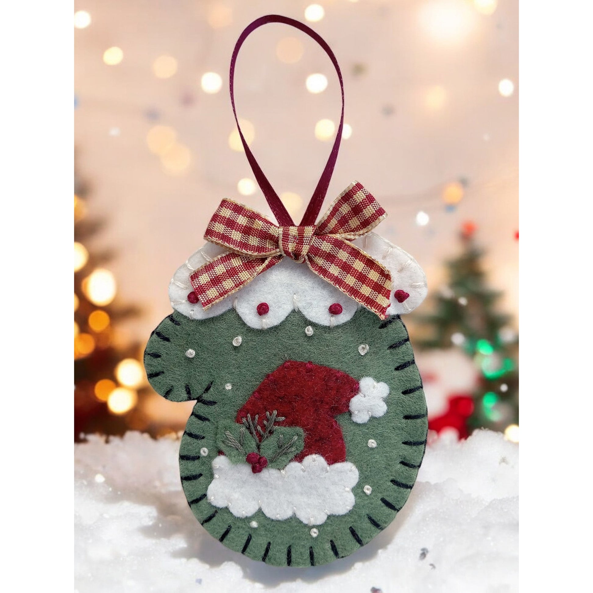 Closeup of mitten ornament with ribbon hanger with bow and Santa Hat applique.