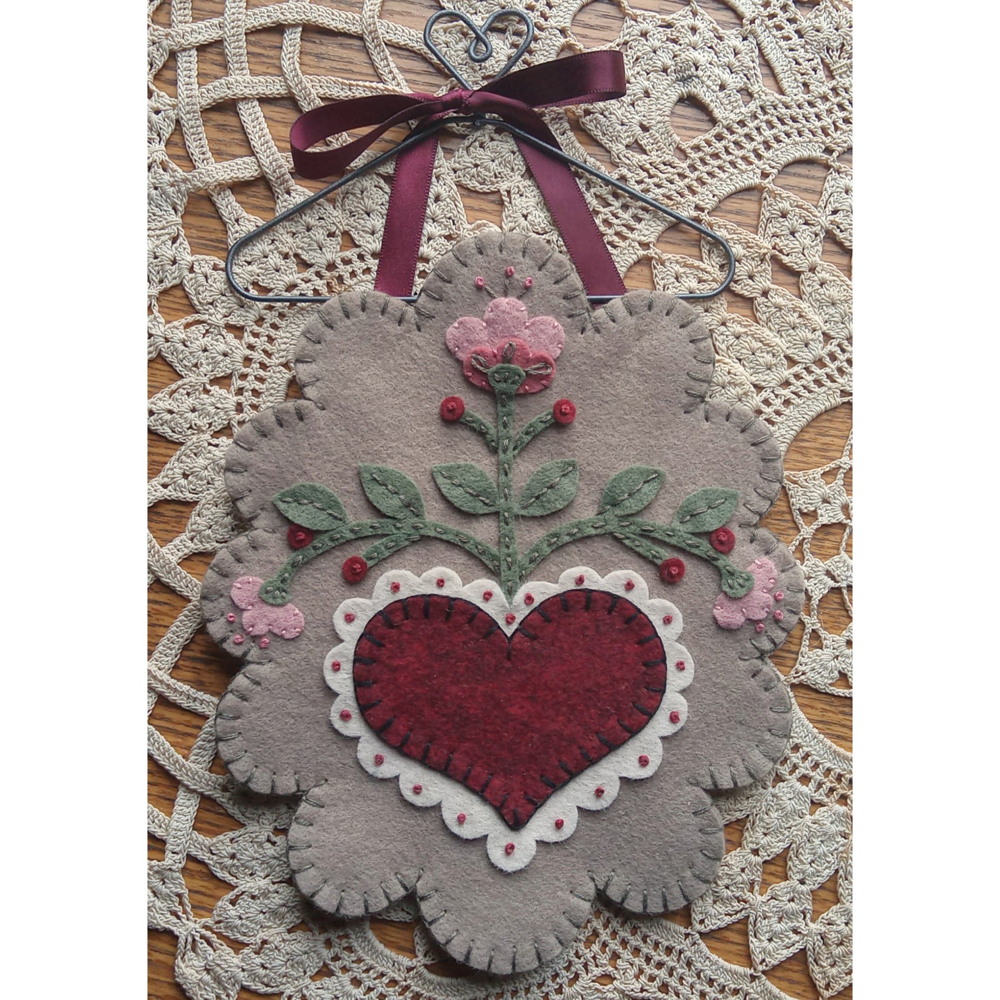 Mini mat shown with a ribbon for hanging. Flower on top of heart with three branches of the flowers. All scalloped into an egg-like shape.