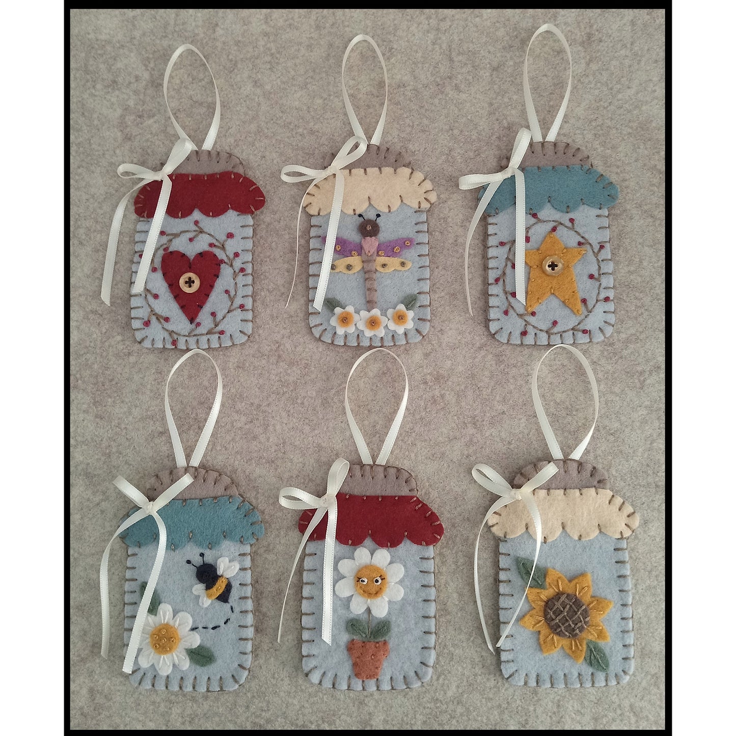 Six adorable wool felt ornaments that look like mason jars.  "Inside" each include: heart with wreath around it, dragonfly with flowers, star with wreath around it, bee buzzing off a flower, happy potted flower/daisy, and sunflower.