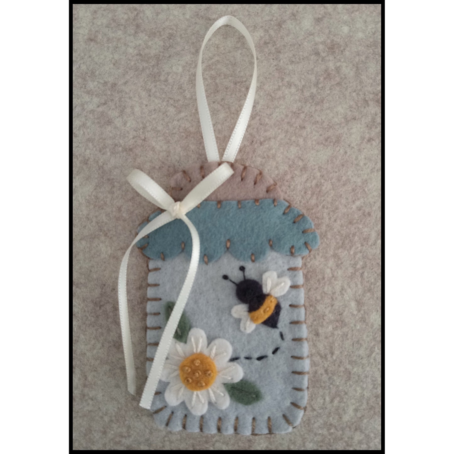 Adorable wool felt ornament close up so you can see how cute.  Inside is a bee buzzing off a daisy.