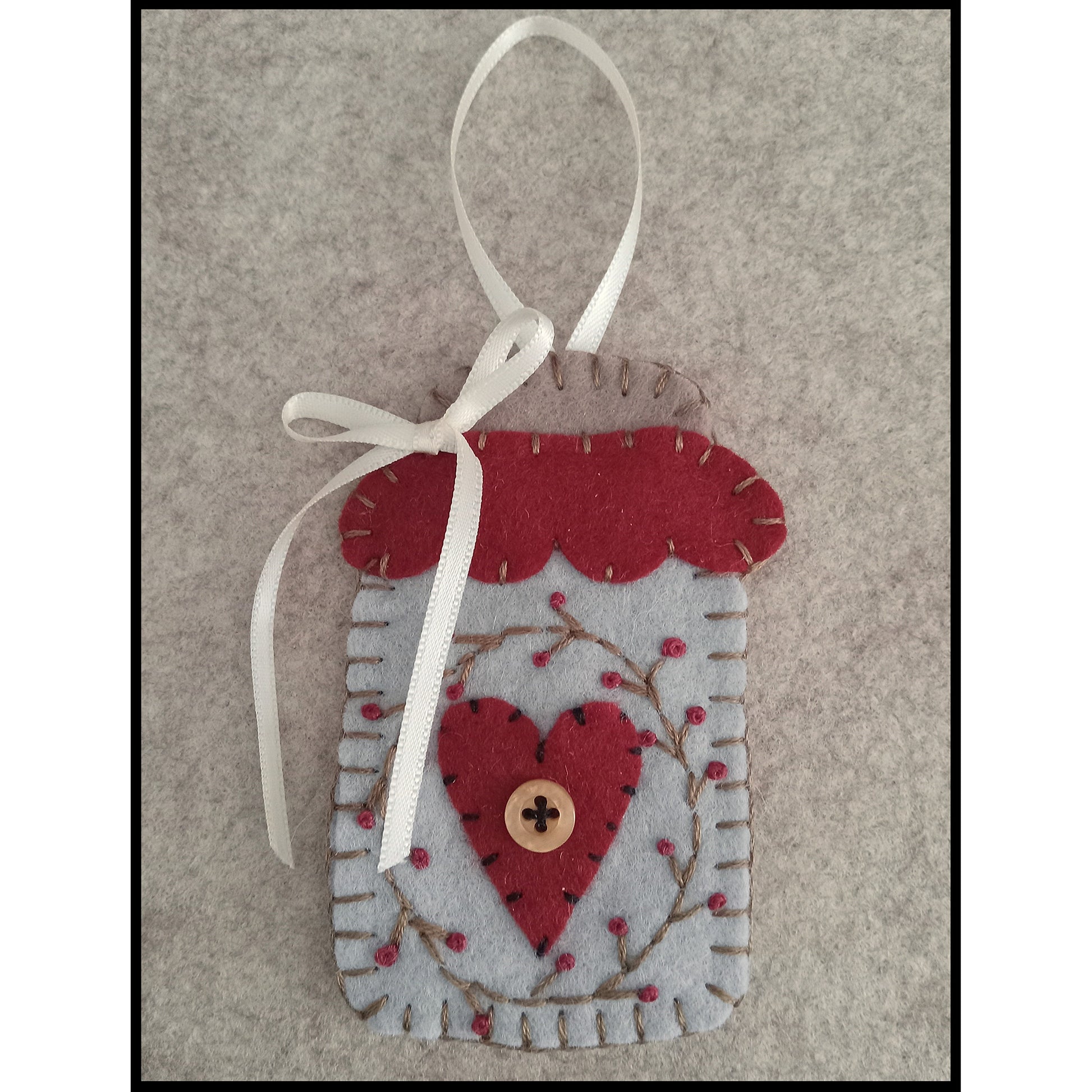 Adorable wool felt ornament close up so you can see how cute. Inside jar is a heart with button and wreath embroidered around it.