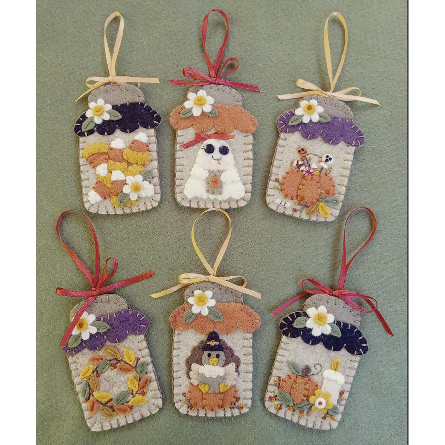 6 adorable mason jar ornaments using wool felt. Inside each is a different fun fall item. These include: candy corns with a flower, ghost with a bag, pumpkin filled with candy, fall wreath, turkey sitting on a pumpkin, and pumpkin and candle.