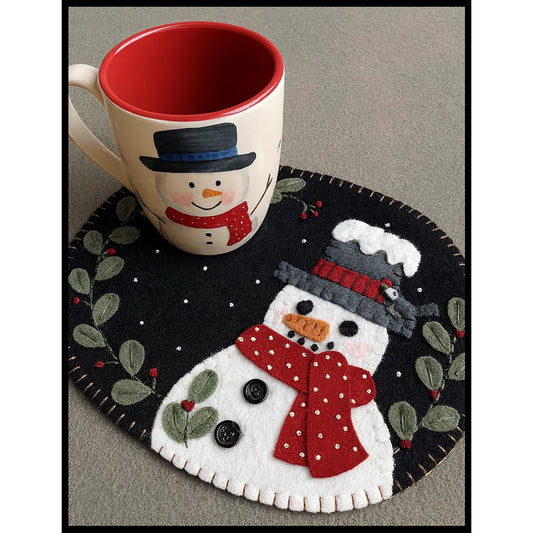 Adorable winter mug rug features a snowman with snow on his hat and a scarf. Other side of the mug rug has space where you can put a mug, like in this photo.  There is some holly and pin pricks of snow.