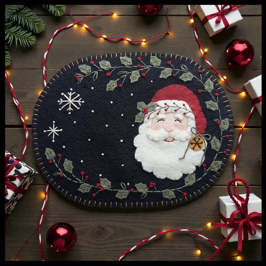 Festive Jolly Old Saint Nick mug rug features holly border, a couple of embroidered snowflakes and a life-like Santa Claus.
