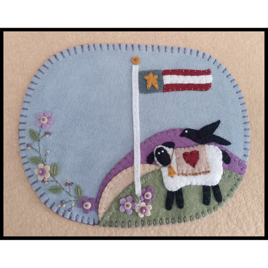 Show your patriotic spirit with this beautifully detailed wool applique mug rug, designed to celebrate our country's 250th Anniversary. This heirloom-style piece features a hand-stitched sheep and crow with an American flag and some pretty pastel flowers.