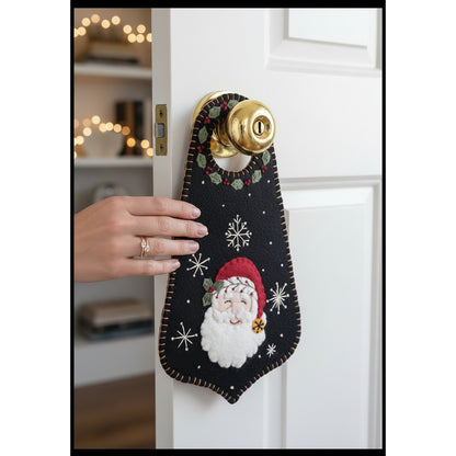 This sweet wool door hanger features a smiling Santa surrounded by winter greenery, berries, and pretty snowflakes. 