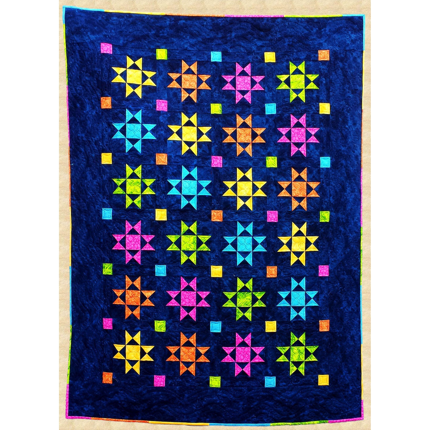 Traditional Ohio Star blocks in bright colors sparkle against a dark blue night sky in this cozy quilt. The multicolor binding picks up the star colors for a creative finish.