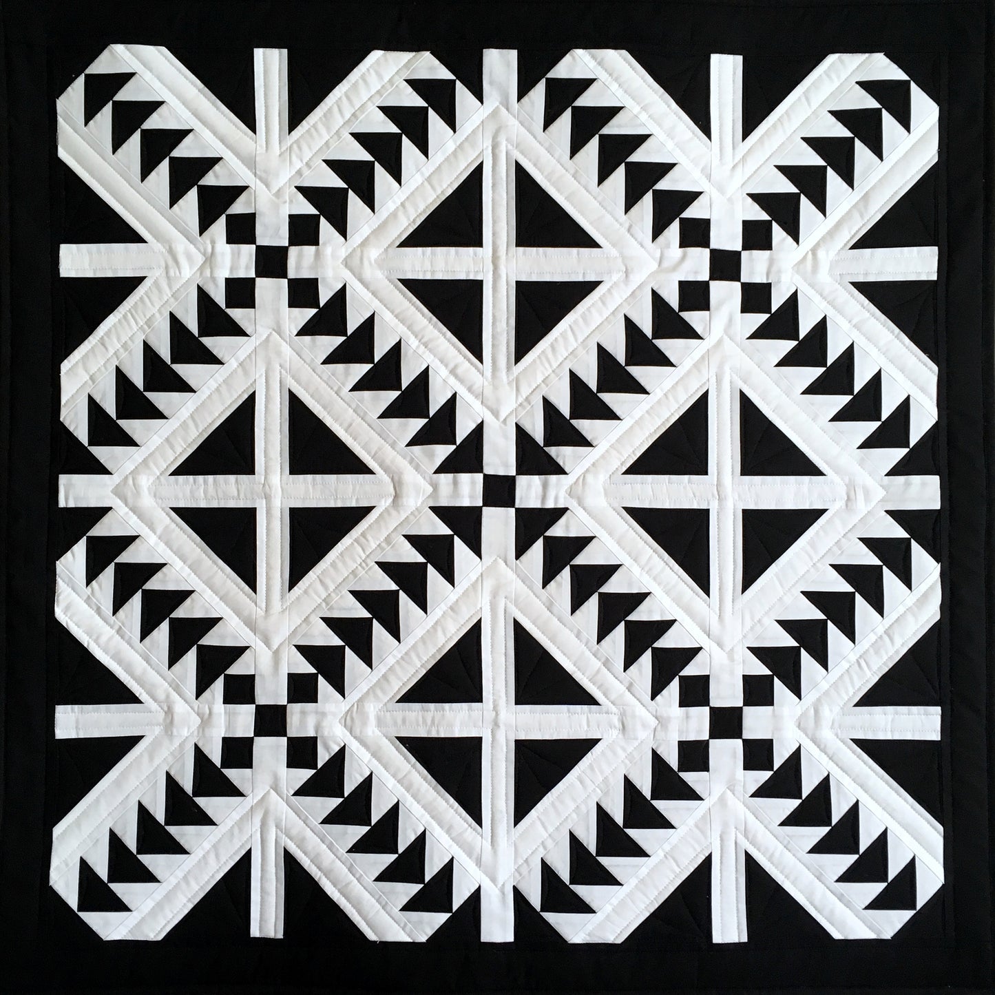 Cross Flight quilt is a quilt in black and white with diamonds cut into four and flying geese blocks.