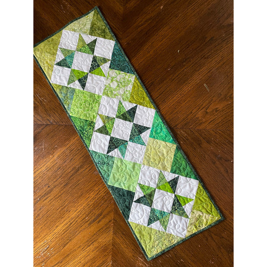 A green and white quilted table runner featuring a decorative star pattern.