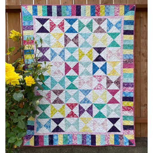 Keeping Time quilt features bright colored hour glasses in up-and-down and side-to-side directions with bright colored stripped border.