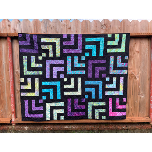 Beautiful and vibrant quilt with squares of stripes which look like rectangular Wi-Fi symbol in purple and blue with black background. Shown hanging.