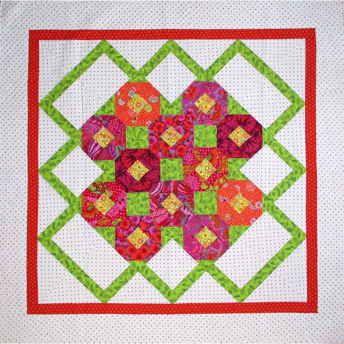 Sweet, floral quilt features a green zig-zag pattern on the outside of a grouping of colorful snowblock flowers.