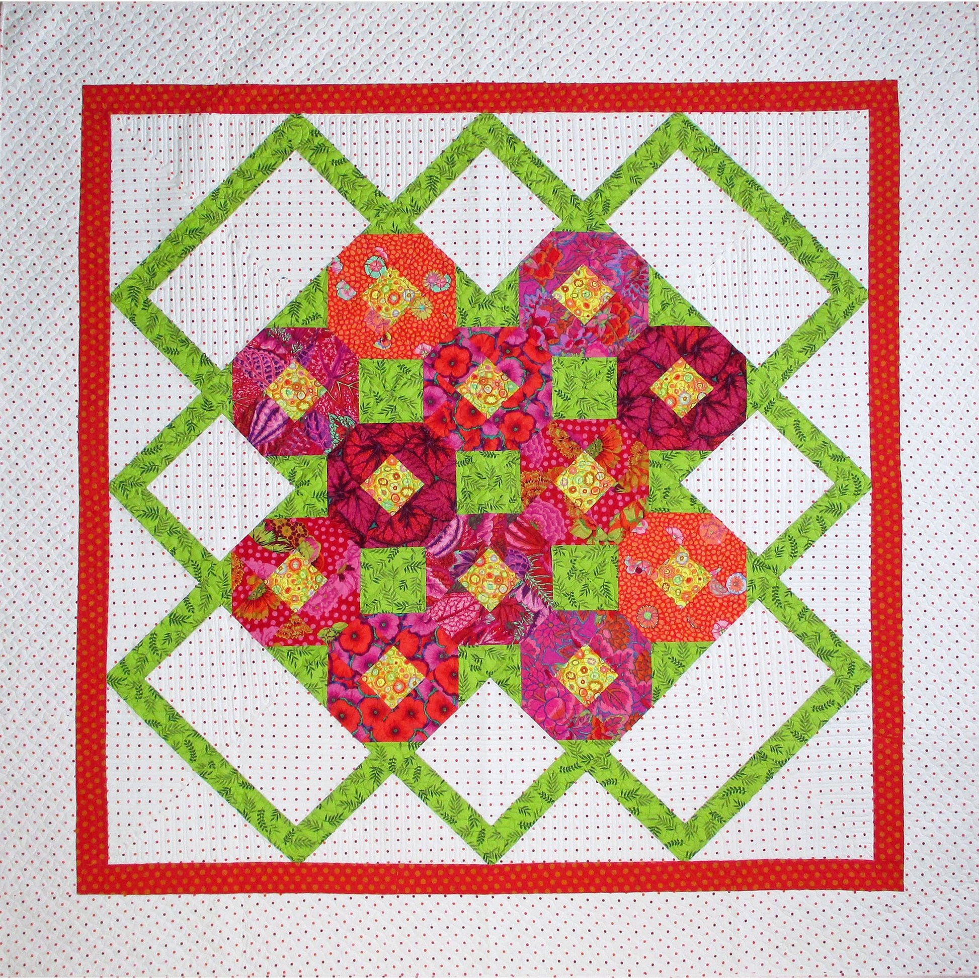 Sweet, floral quilt features a green zig-zag pattern on the outside of a grouping of colorful snowblock flowers.